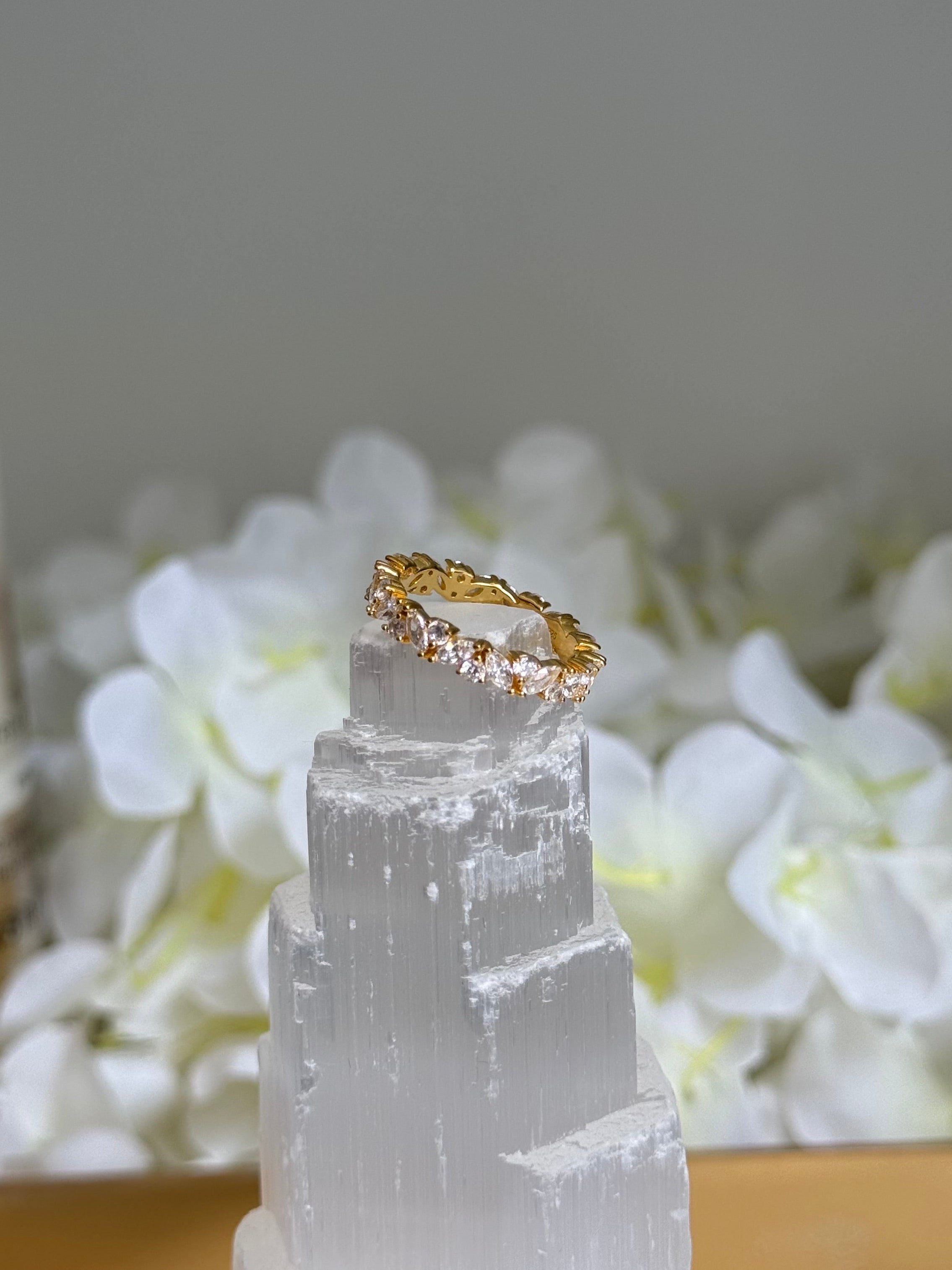Gold ring on a clear crystal with white flowers in the background