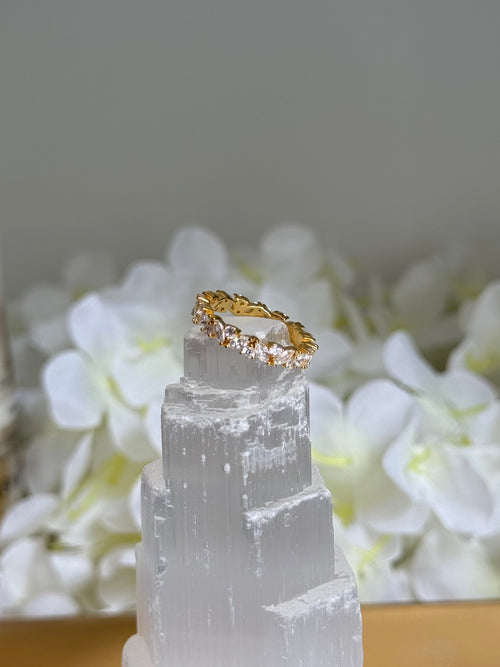 Gold ring on a clear crystal with white flowers in the background