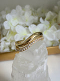 Gold ring with diamonds on a white stone with flowers in the background