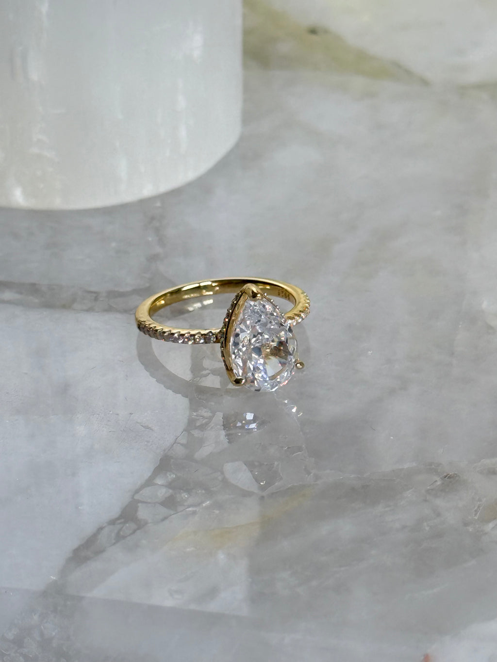 Gold ring with a large diamond on a marble surface