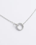 Silver necklace with a round pendant on a light gray background