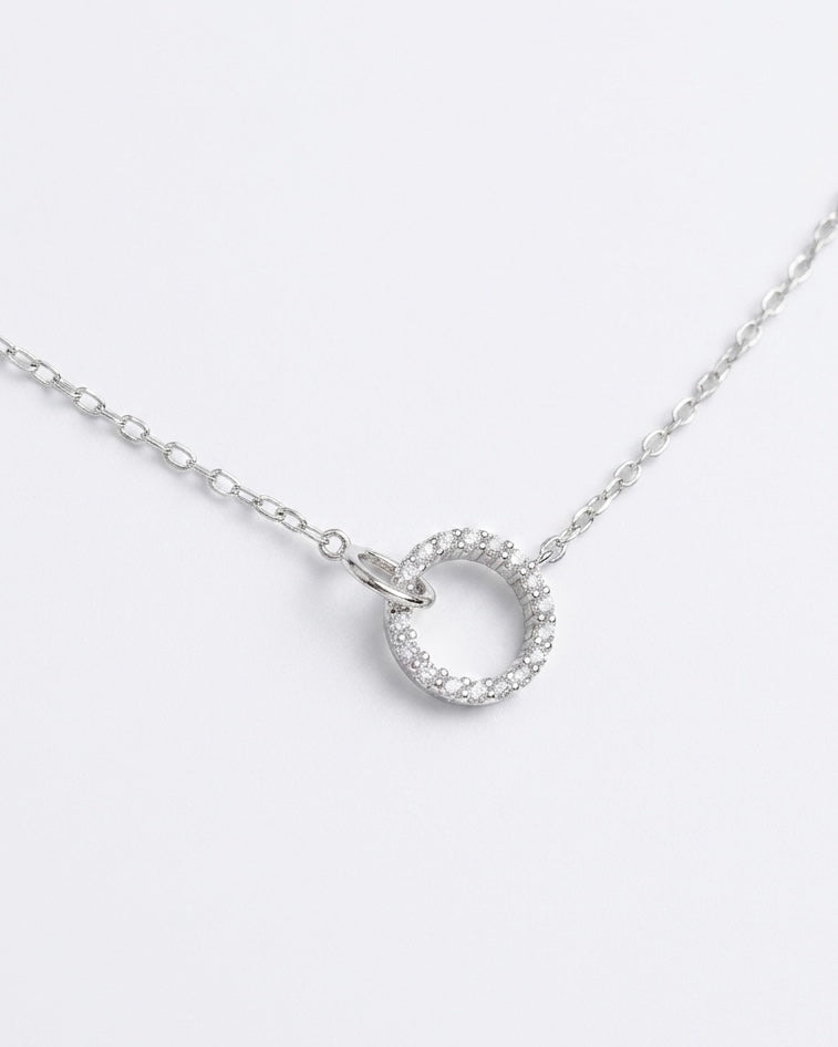 Silver necklace with a round pendant on a light gray background