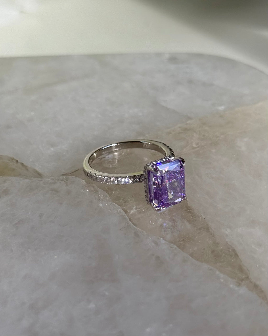 Silver ring with a purple gemstone on a marble surface
