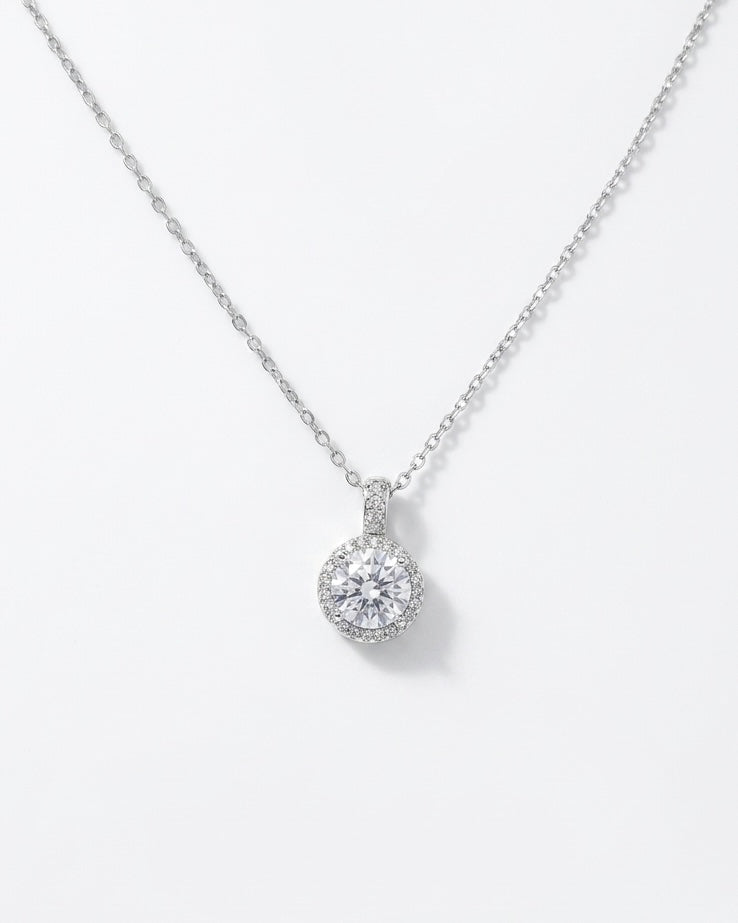 Silver necklace with a round diamond pendant on a light gray background