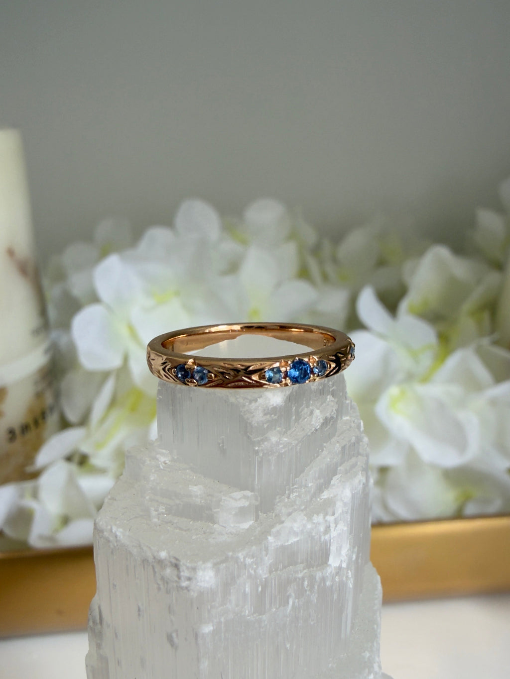 Gold ring with blue stones on a crystal and flower background