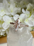 Rose gold ring with diamond on a decorative stand with flowers and crystals