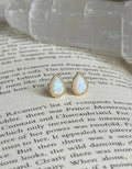 Teardrop-shaped earrings with gold accents on a book page
