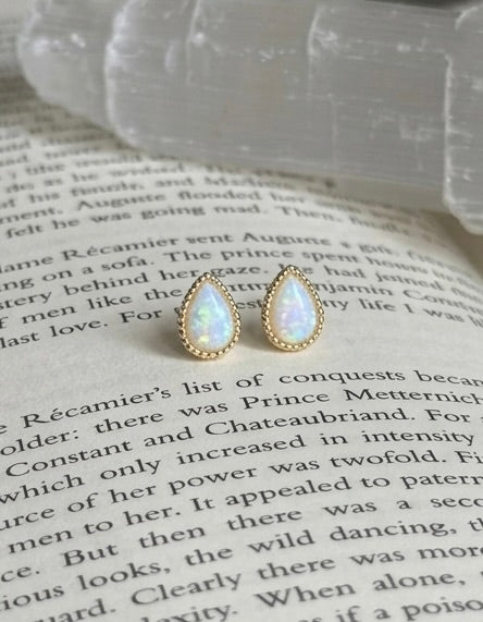 Teardrop-shaped earrings with gold accents on a book page