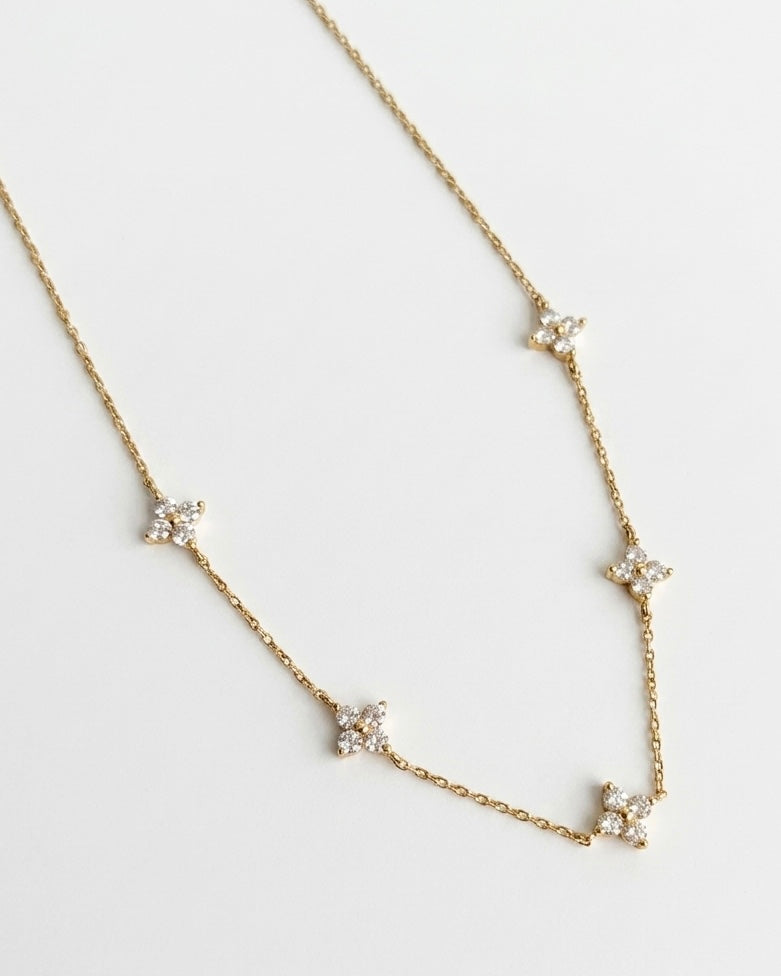 Gold necklace with star-shaped pendants on a light gray background