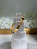 Gold bracelet on a crystal with a soft white floral background