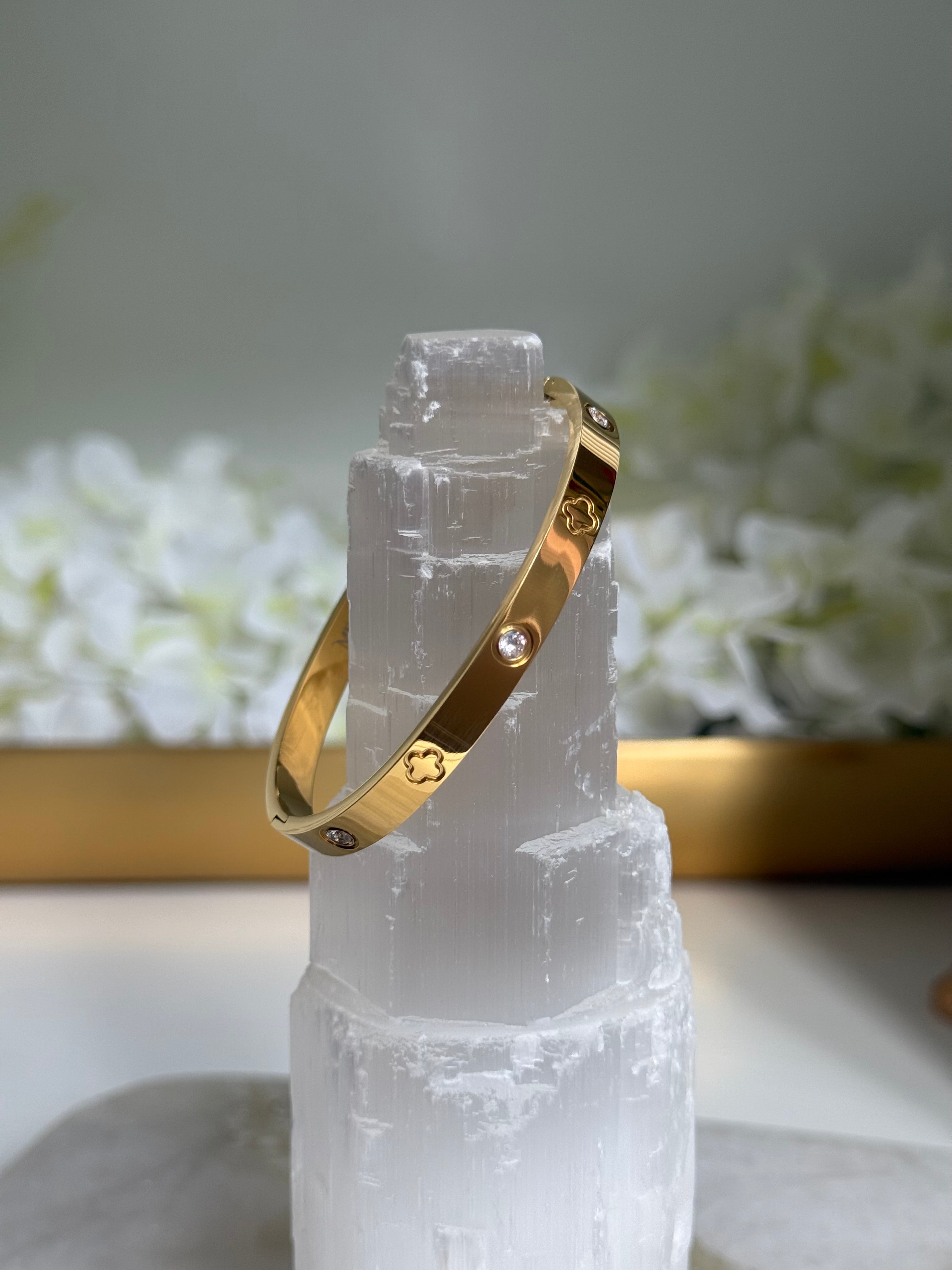 Gold bracelet on a crystal with a soft white floral background