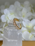 Gold ring with small diamonds on a white stone surface with white flowers in the background