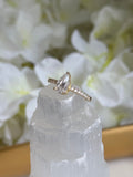 Gold ring with a clear gemstone held over white flowers and crystals