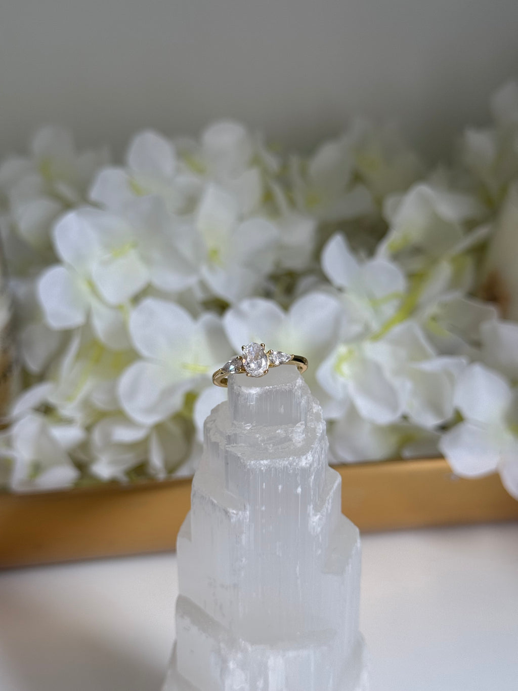 Diamond ring on a decorative crystal with white flowers in the background