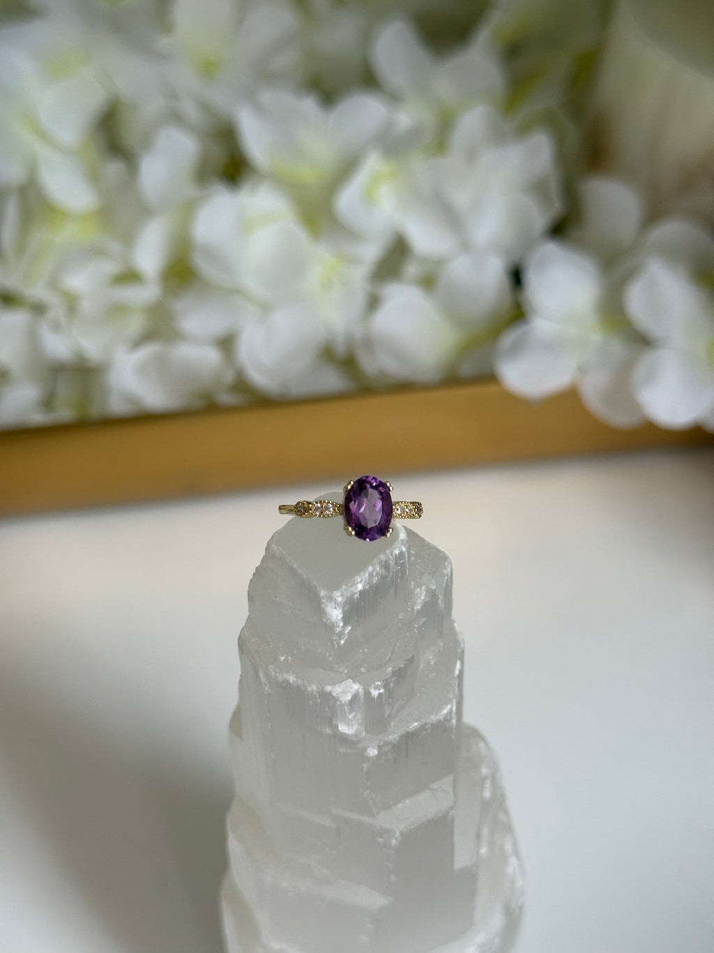 Ring with a purple gemstone on a crystal and floral background